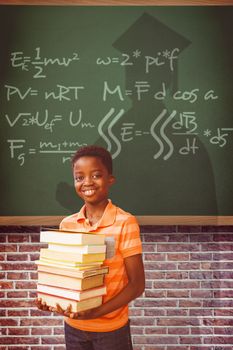 Portrait of cute boy carrying books in library against green