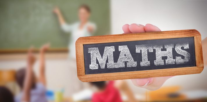 The word maths and hand showing chalkboard against pupils raising their hands during class