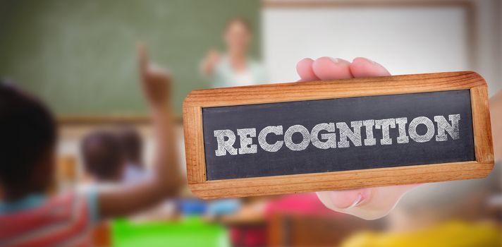 The word recognition and hand showing chalkboard against pupils raising their hands during class