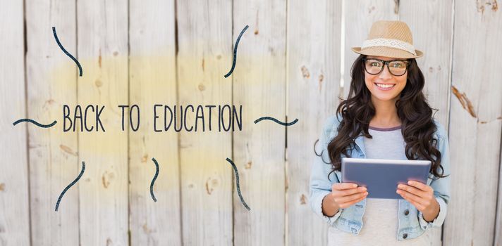 The word back to education against pretty hipster smiling at camera holding tablet