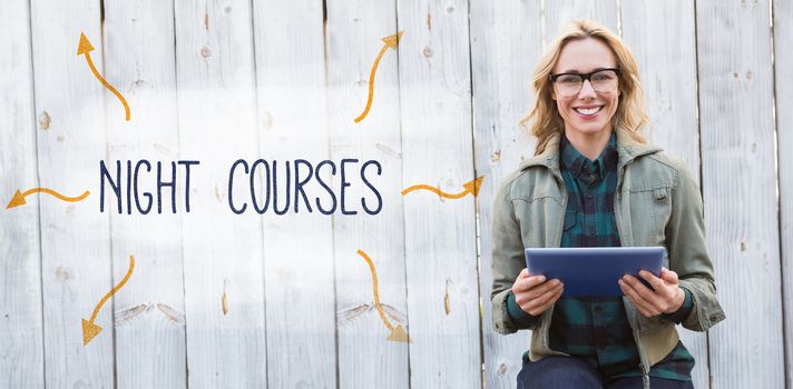 The word night courses against smiling blonde in glasses using tablet pc