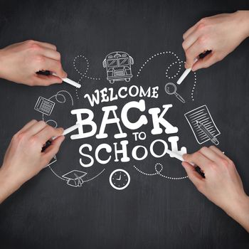 Multiple hands writing with chalk against blackboard