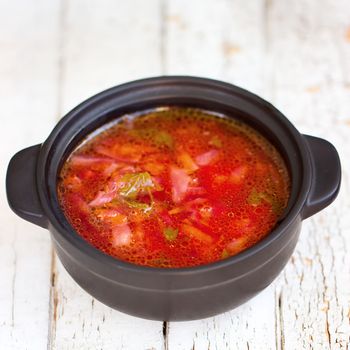 Red borsch. The traditional Ukrainian dish. In a small saucepan. On the white table