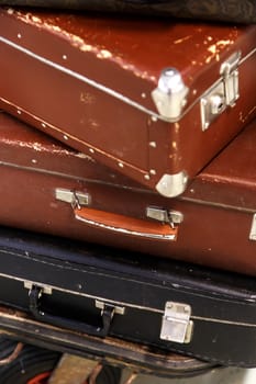 Close up detailed view of old nostalgical brown leather and fabric suitcases on end.