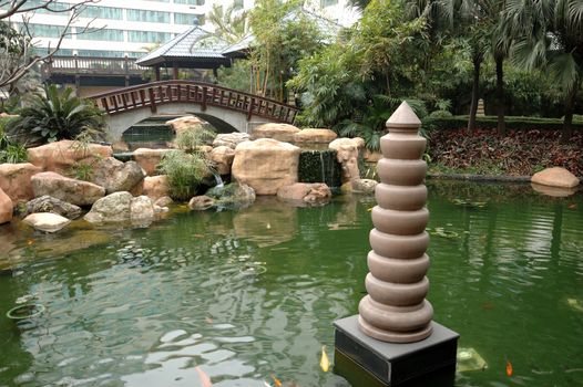 Traditional Chinese garden in Guangzhou with pagoda, pond, rocks and colorful fishes. 