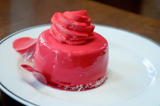 Red Cream cake with frosting decorated with a rose.