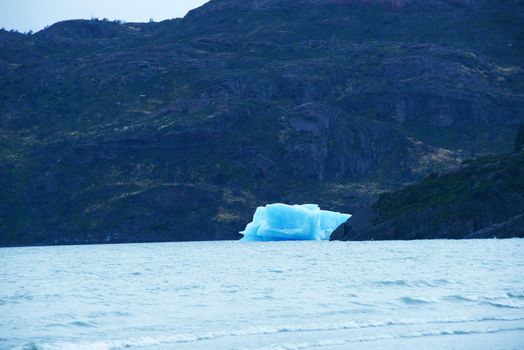 a blue iceberg from a glacier was floating in lake grey