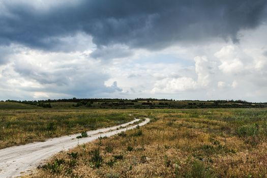 The rural dirt road, beautiful countryside in cloudy weather