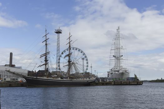 Two ships in docks and a ferris wheel.