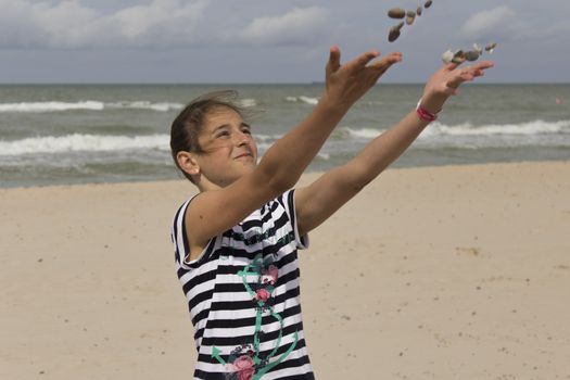 Girl throwing pebble stones on the beach.