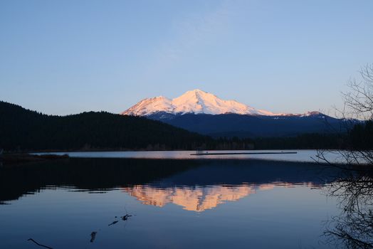 a reflection of mount shasta over a lake during sunset