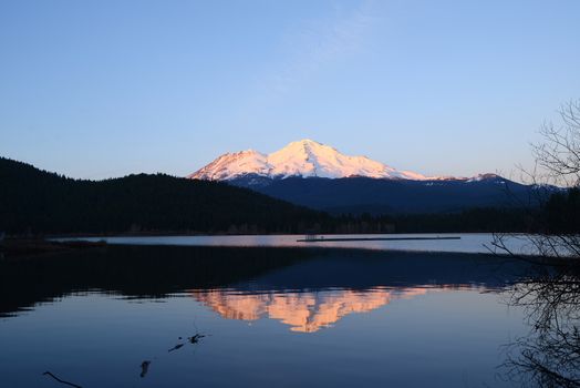 a reflection of mount shasta over a lake during sunset