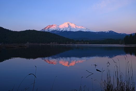 a reflection of mount shasta over a lake during sunset