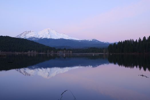 a reflection of mount shasta over a lake during sunset