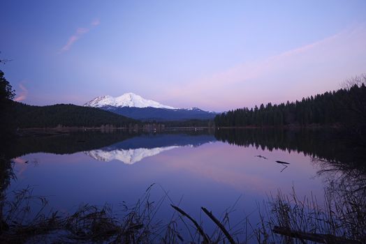 a reflection of mount shasta over a lake during sunset