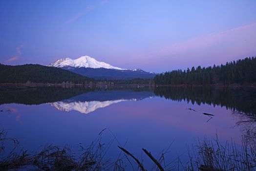 a reflection of mount shasta over a lake during sunset