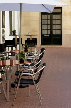 Elegant Street Cafe with Flower Pots, Wooden Tables and Stainless Steel Chairs Outdoors. Focus on Foreground