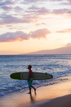 Ocean beach scene with man carrying surfboard to water