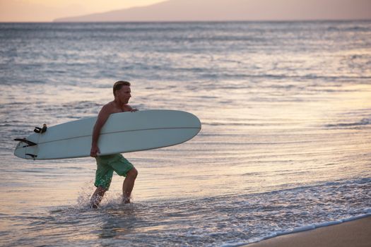 European man carrying his surfboard out of the water