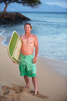 Single adult Caucasian male outdoors with surfboard at shoreline