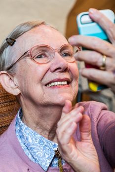 Happy old woman in pink sweater taking a smiling selfie