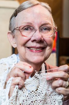 Smiling old woman with crochet looking at camera