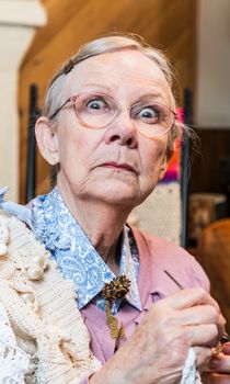 Startled old woman with crochet in livingroom