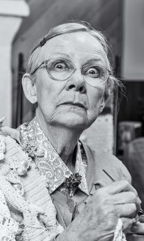 Scared old woman with crochet in living room