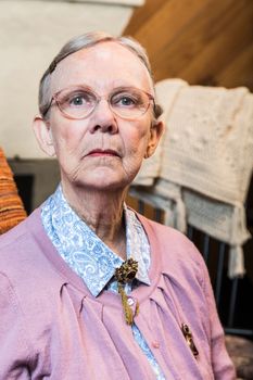 Old woman in pink sweater sitting straight and stern