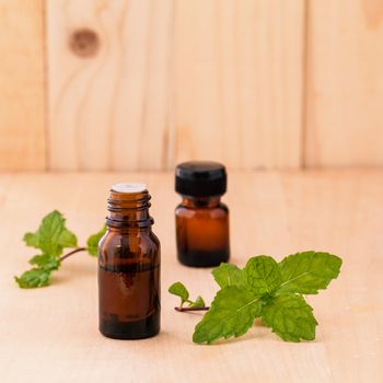 Bottle of mint essential oil on wooden background with selective focus.