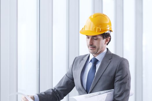 Architector in hardhat and business suit with construction plans