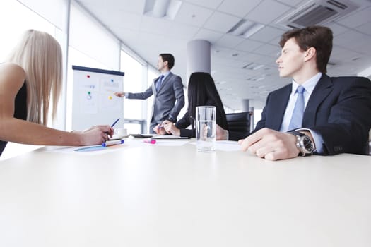 Workers at business meeting looking at presentation of financial reports in modern office