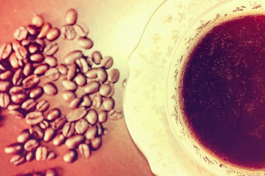 Coffee beans and cup of hot coffee. Vintage instagram picture. Antique porcelain cup.