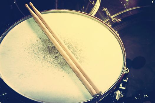 Drums conceptual image. Picture of drums and drumsticks lying on snare drum. Retro vintage instagram picture.