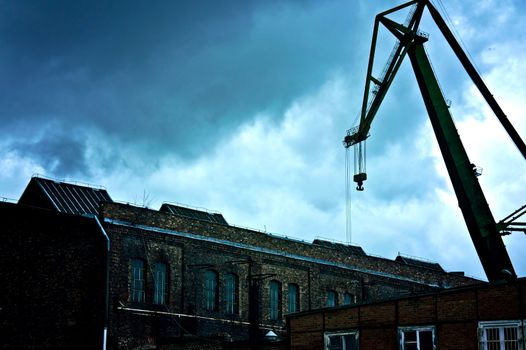 Dark and sullen clouds over old abandoned industrial area with cranes.