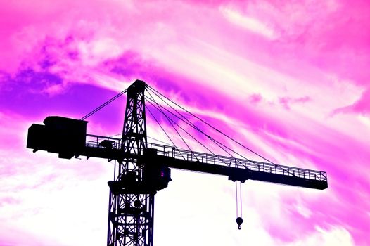 Industrial conceptual image. Purple clouds over industrial area with crane.