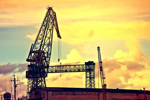 Industrial conceptual image. Dark and sullen clouds over industrial area with cranes.