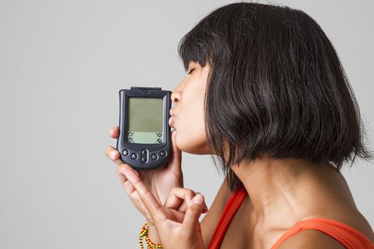 Philipino woman wearing a low cut orange dress kissing an old digital personnal assistant