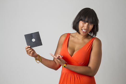 Philipino woman wearing a low cut orange dress holding a five inch floppy drive