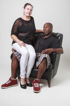 caucasian woman, with distrub expression, sitting on a black man lap