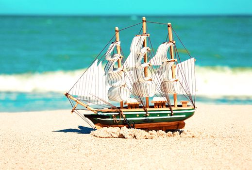 Souvenir conceptual image. Model of ship in the sand near the ocean.