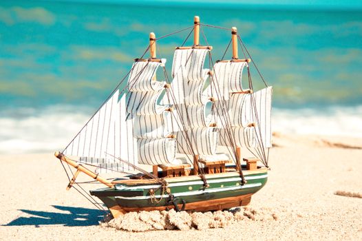 Souvenir conceptual image. Model of ship in the sand near the ocean.