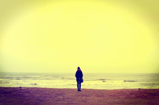 Emotion conceptual image. Lonely woman walking on the beach. Instagram vintage picture.