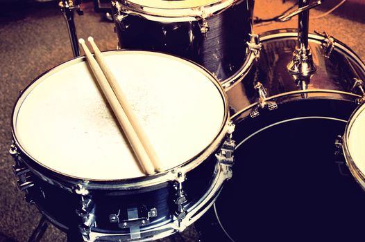 Drums conceptual image. Picture of drums and drumsticks lying on snare drum. Retro vintage instagram picture.