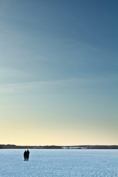 Iced lake in denmark in winter with people on it at sunset