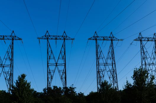 supports of high-voltage power lines against the blue sky