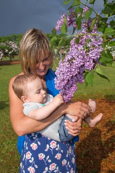 pretty little baby boy with mother  near lilac tree