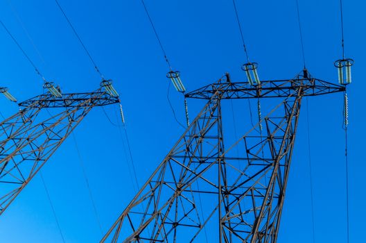 supports of high-voltage power lines against the blue sky