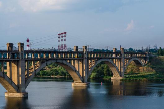 road and rail split-level bridge over the river on a background of blue sky in the city