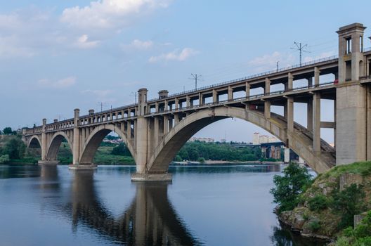 road and rail split-level bridge over the river on a background of blue sky in the city